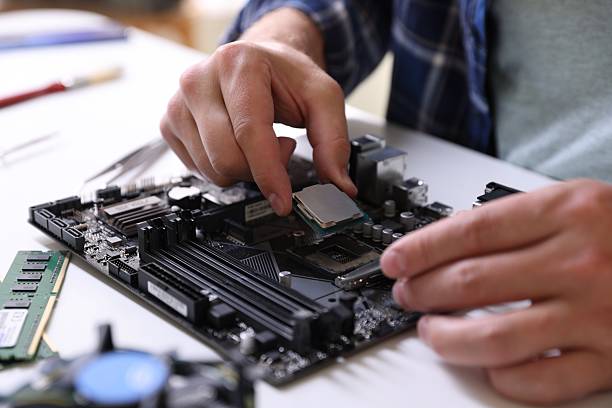 istock Man installing computer chip onto motherboard at white table, closeup 2224066980