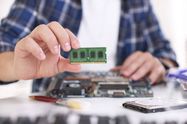istock Man installing computer chip onto motherboard at white table, closeup 2224067030