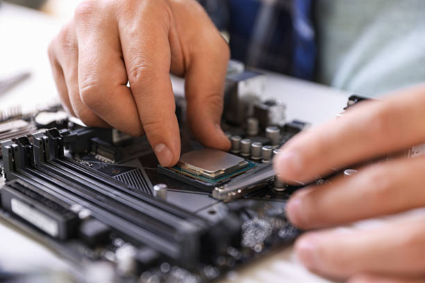 istock Man installing computer chip onto motherboard at white table, closeup 2224067055