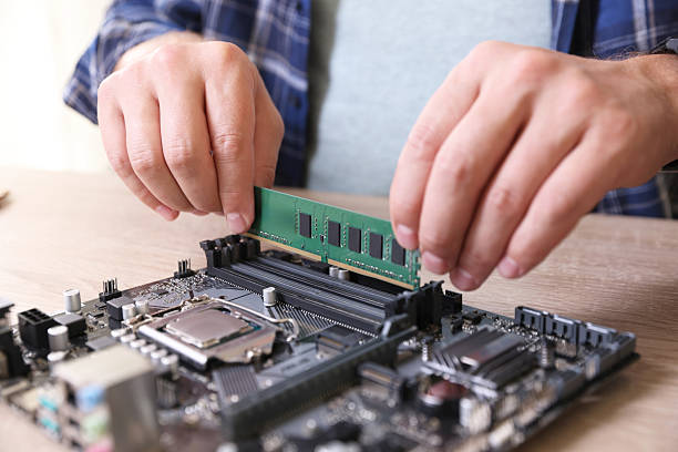 istock Man installing computer chip onto motherboard at wooden table, closeup 2224067058