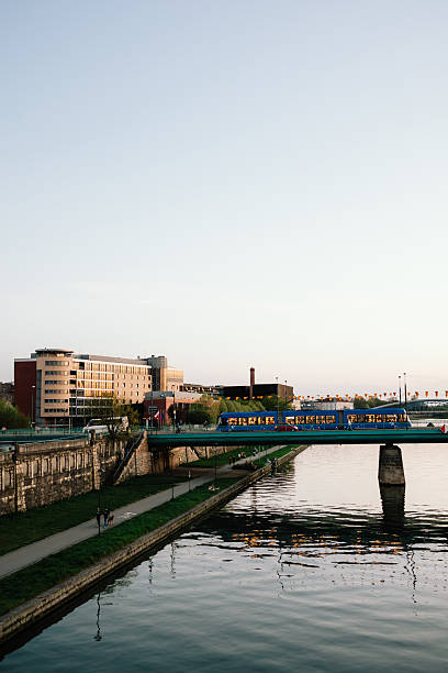 istock Vertical screen: Krakow cityscape glowing at sunset, featuring blue tram crossing bridge over the tranquil Vistula River, with modern buildings creating vibrant urban backdrop. Tram traversing bridge 2224067585
