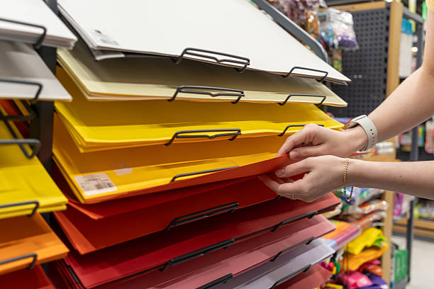 istock Person's hands carefully selecting colorful sheets of paper from a large display rack, ideal for art projects, craft activities, and school supplies shopping 2224068399