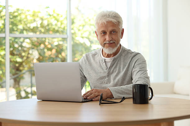 istock Senior man using laptop at table indoors 2224069052