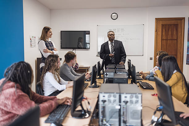 Multiracial students using computers during business class wearing safety masks at school