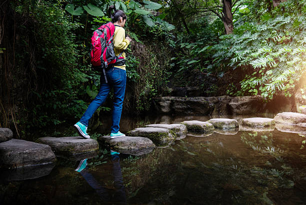 istock Female backpacker walking on stepping stones 2224070330