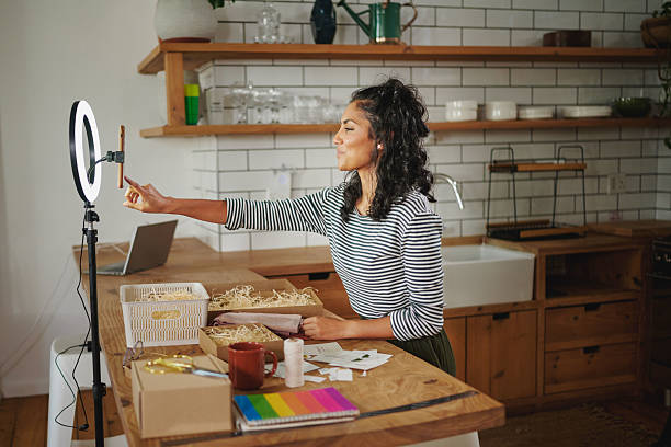 istock Creative young woman pressing the record button as she creates content with a ring light and smart phone for her online sustainable business at home. 2224070670