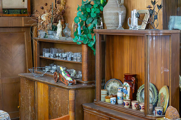 istock Vintage display cabinets filled with glassware, ceramics, and decorations, including dried plants and an old radio – classic retro interior with a collection of ornaments. 2224074839