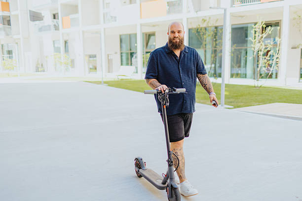 istock Smiling young man exploring city on his push-scooter during sunny summer day 2224075289