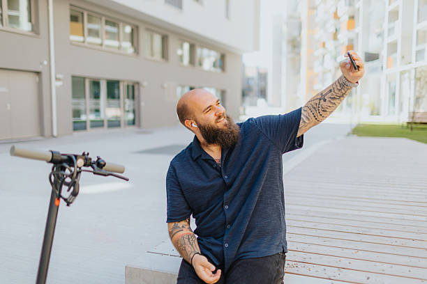 istock Cheerful young man taking selfie on smart phone while sightseeing city on push-scooter 2224075481