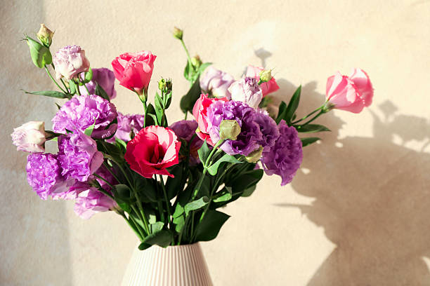 istock Vase with beautiful eustoma flowers near beige wall, closeup 2224076562