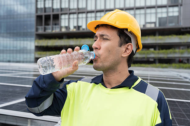 istock Male engineer drinking water on rooftop of building with solar cell panel blur background. Worker drinking water while maintenance solar panel on rooftop 2224076878