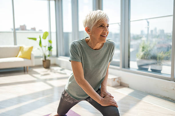 istock Active senior woman stretching during yoga exercise at home with sunlight 2224086440