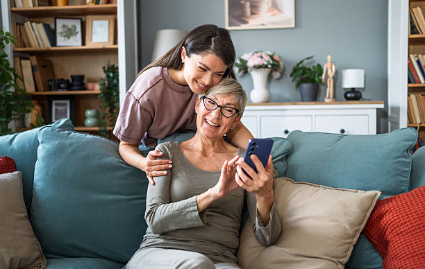 istock Mother and daughter laughing while using smartphone at home 2224086784