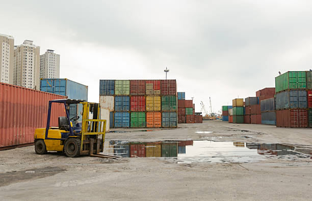 istock Stacked Shipping Containers with Parked Forklift at Cloudy Midday Port 2224087556