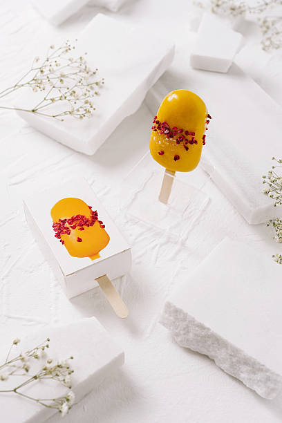 Delicious frozen mango treats decorated with edible flowers on a white surface