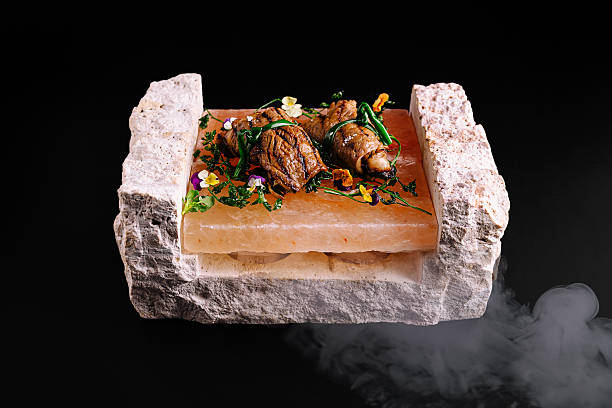 Delicate seafood is artfully arranged on a Himalayan salt block, surrounded by herbs and edible flowers. This elegant dish showcases modern culinary techniques and presentation.