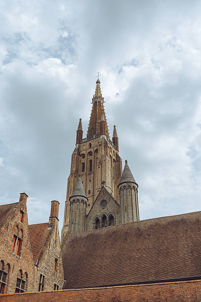 The Church of Our Lady (Onze-Lieve-Vrouwekerk) in Bruges, Belgium, is a Roman Catholic church renowned for its towering spire, which, at 115.6 meters, is the tallest structure in the city and the third tallest brick tower in the world . Construction began in the 13th century and continued into the 15th century, showcasing a blend of Gothic and Baroque architectural styles .\nInside, the church houses several notable artworks and historical monuments. Among these is Michelangelo's Madonna and Child, a white marble sculpture created around 1504, which is one of the few works by the artist to leave Italy during his lifetime . Additionally, the church contains the tombs of Charles the Bold and his daughter Mary of Burgundy, both significant figures in European history .\nThe church is an active place of worship and a testament to Bruges' rich cultural and architectural heritage