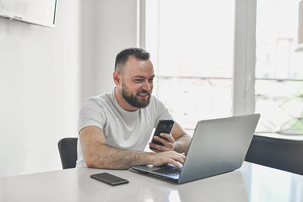istock Content Young Man Reading Satisfying Work Update on Laptop in Clean Office Space 2224100047