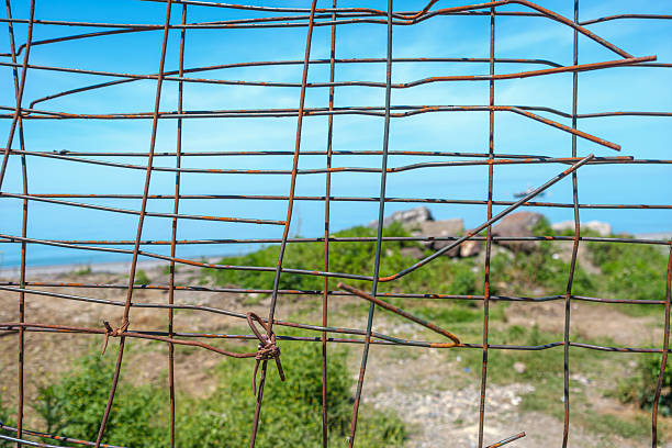 Barbed old wire fence with coastal view. Framing a serene coastal landscape beyond. Capturing the contrast between confinement and the openness of nature.