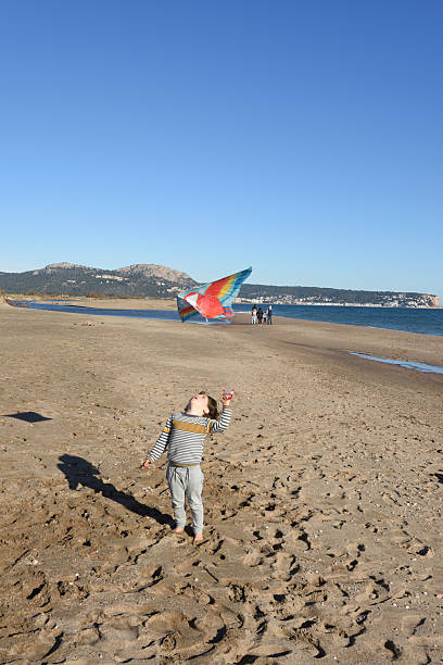 front view of a boy playing with a kite on the beach