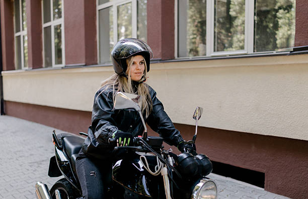 istock Joyful young woman riding a motorcycle on an adventure through a natural setting 2224106041