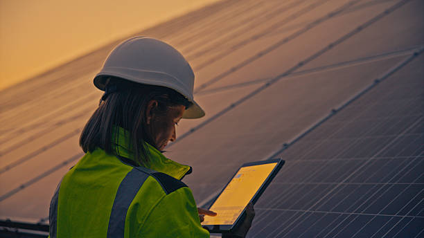 istock Professional Female Engineer Monitoring Solar Panel Performance In High-Visibility Safety Gear At Dawn 2224108254