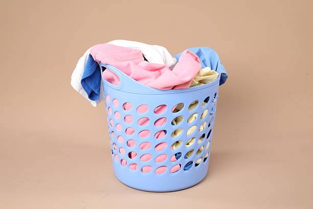istock Plastic basket full of laundry on beige background 2224109273