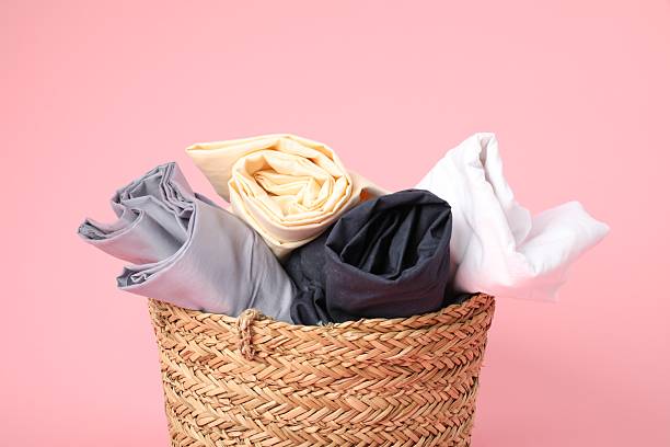 istock Wicker basket full of laundry on pink background, closeup 2224109291
