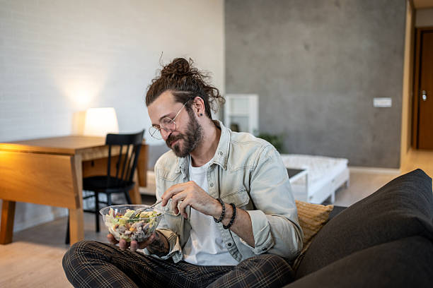istock Young man enjoying a healthy salad at home 2224109929