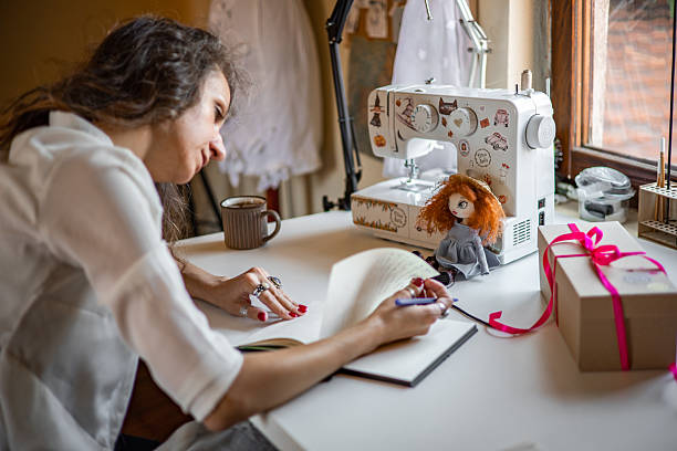 Talented solo creator assembling custom cloth dolls by hand in a thoughtfully decorated creative space, running her independent craft business with passion