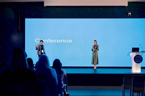 istock Professional Presenter Stepping onto Stage as Crowd and Host Watch 2224110763