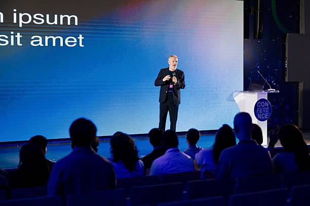 istock Speaker Delivering Keynote Address at Technology Conference in Modern Auditorium 2224111020