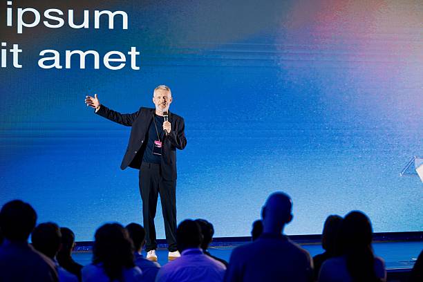 istock Mature Speaker Presenting at Technology Conference with Engaged Audience and Visuals 2224111031