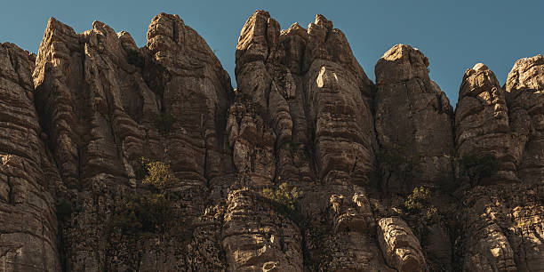Limestone rock formations like pillars with some green vegetation under a blue sky. National park El Torcal de Antequera. Andalucia. Spain.