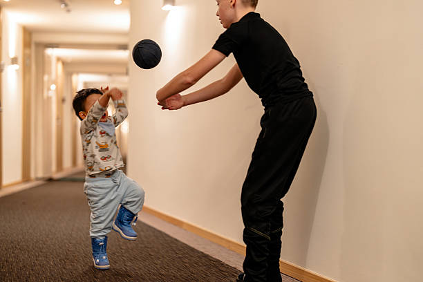 istock Two young boys playing with a ball in a brightly lit hallway 2224111458