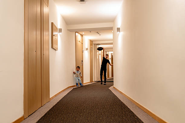 Two children enjoy a playful moment tossing a ball in a clean, sleek hallway. The scene captures a sense of childhood energy and fun amidst a modern architecture setting, highlighted by warm lighting and serene ambiance.