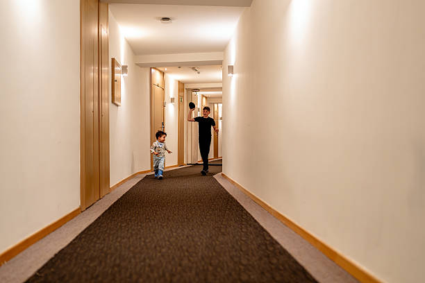 Two cheerful kids enjoy playing with a ball in a brightly lit hotel hallway, creating a lively and joyful atmosphere. The sleek setting enhances the playful moment as they engage in their energetic game, sharing laughter and fun.