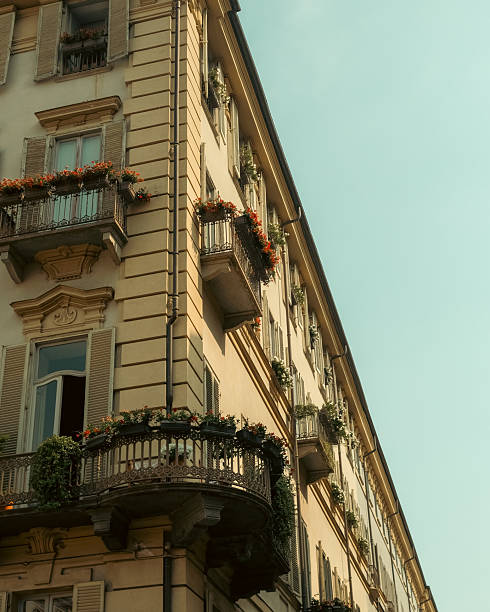 Balconies of flowers line a facade in Turin on a Sunny morning.