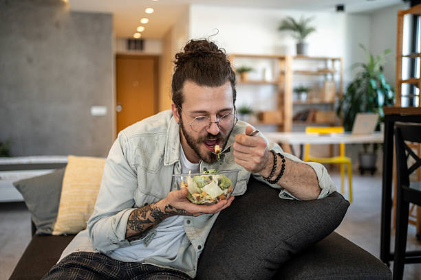 istock Young man eating a fresh salad at home 2224114162