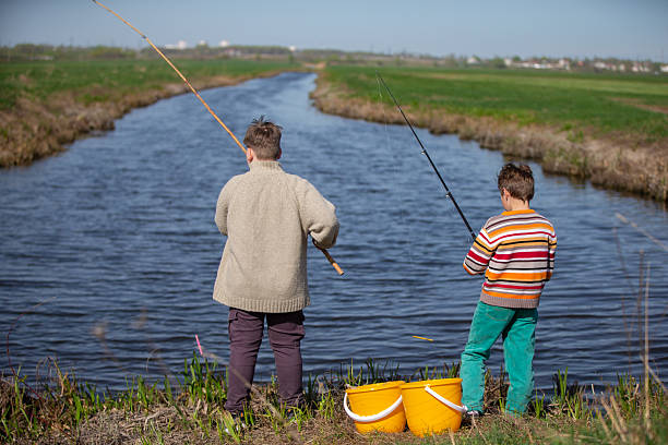 Boys children catch fish near the river. View from behind.