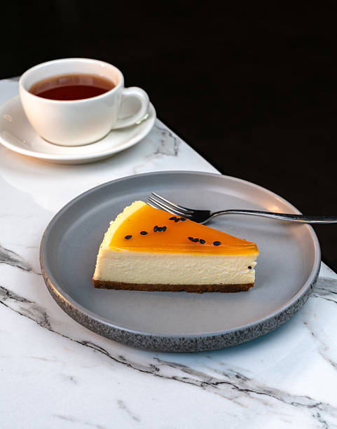 istock Slice of Lemon Cheesecake on Marble Table with Blurred Tea Cup in Background. Elegant desert scene for cafe menus, pastry ads, and lifestyle content. 2224116043