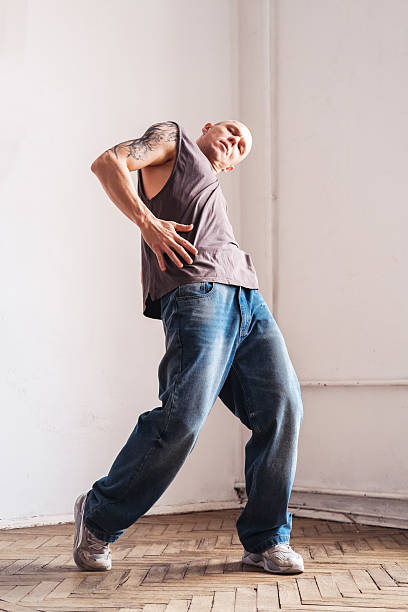 Energetic male dancer wearing headphones, moving rhythmically against contemporary architectural backdrop, expressing urban musical freedom