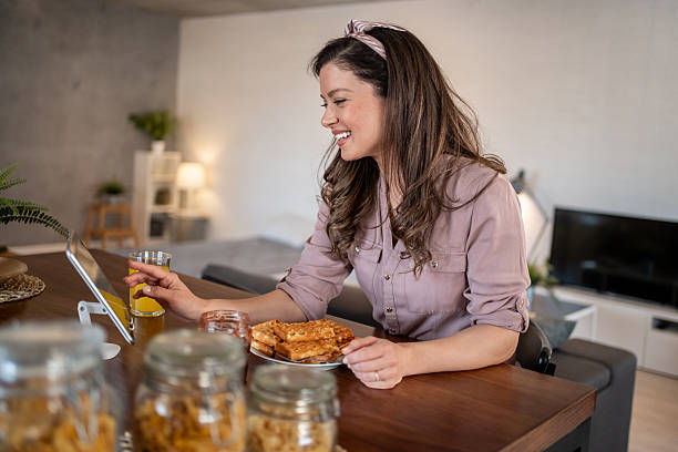 istock Happy woman enjoying breakfast and browsing internet on tablet at home 2224120183