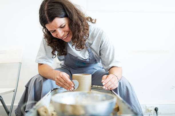 Mid adult woman learning pottering in ceramic studio