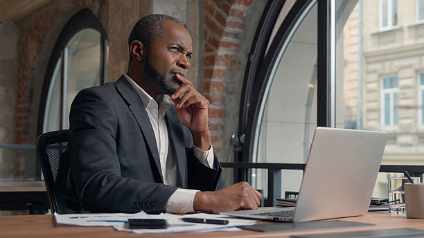 istock African American ethnic adult employer entrepreneur thinking problem solution hesitate decision ponder think come up with idea man business office businessman male manager guy at table typing laptop 2224125563