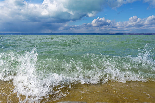 A scenic view of waves crashing on a shore under a cloudy sky, capturing the beauty of nature.