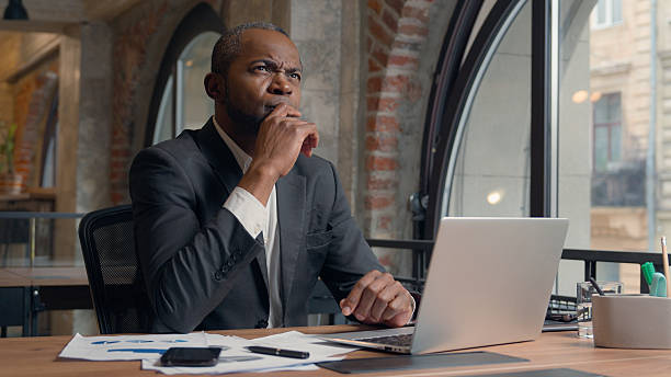 istock African American ethnic adult employer entrepreneur thinking problem solution hesitate decision ponder think come up with idea man business office businessman male manager guy at table typing laptop 2224126317