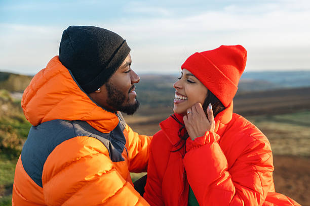istock Couple enjoying a joyful moment together while sitting on a hillside during a sunny day in a cozy winter setting with mountains in the background 2224127148