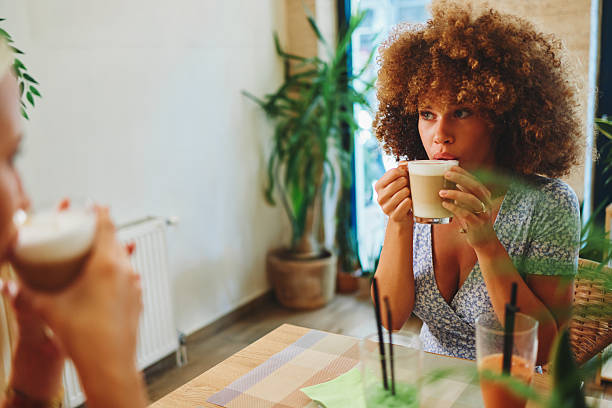 Two friends savoring coffee in a plant-filled cafe