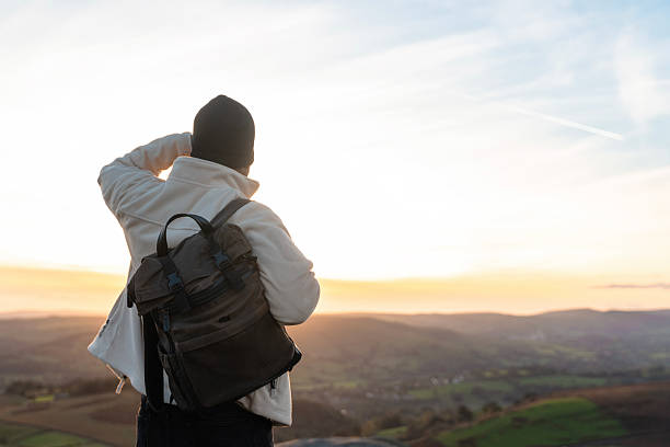 istock Man with backpack enjoys sunrise view on hillside, capturing scenic landscape in rural area during early morning hours 2224128018